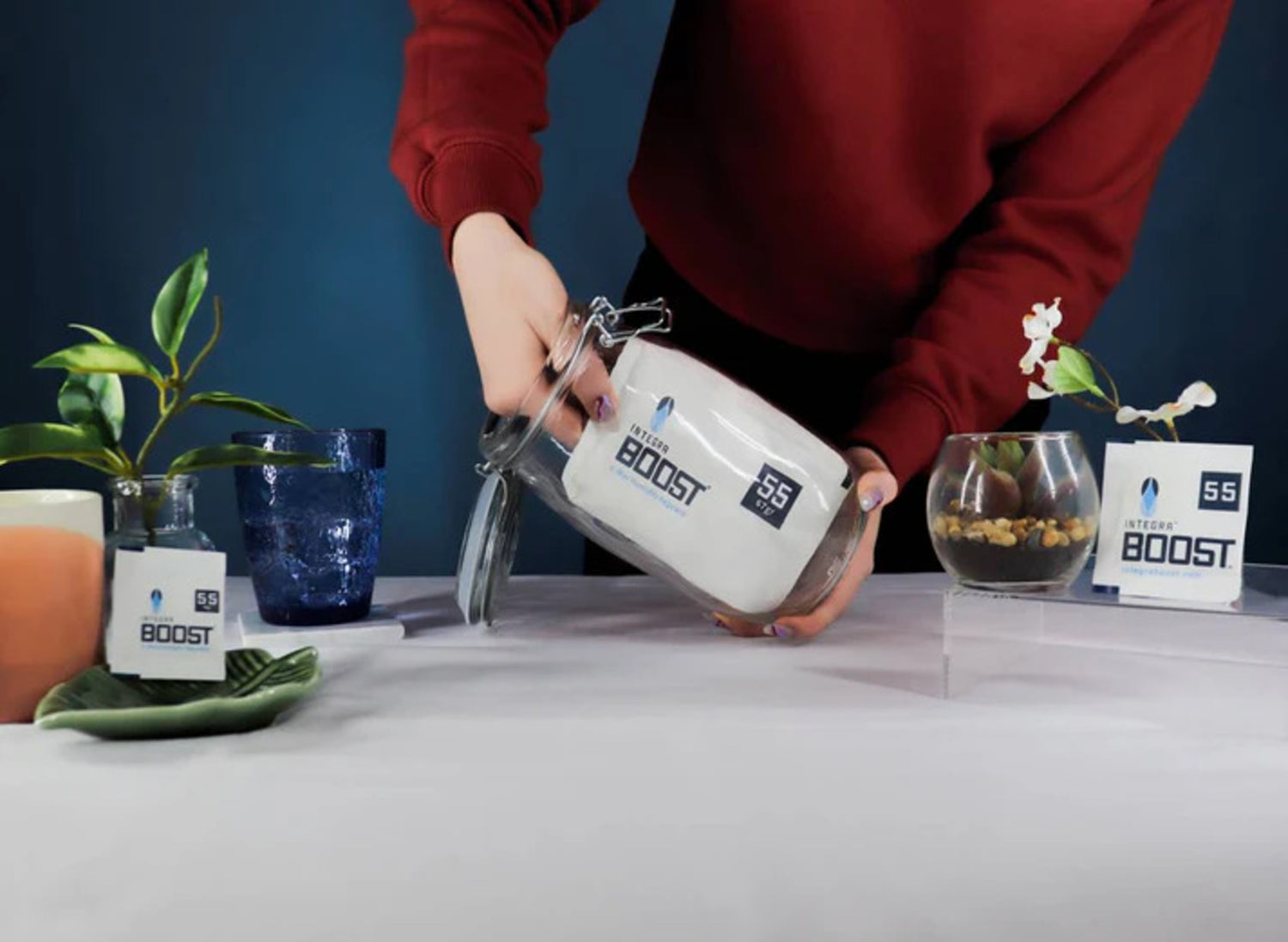 Green jar, white pump bottle, and two white pouches with cannabis leaves on labels, surrounded by cannabis leaves on green background