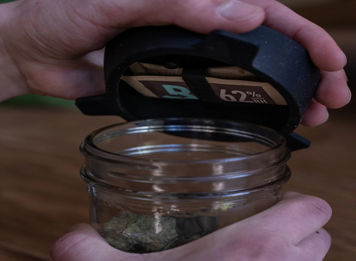 Two glass jars with cork lids containing green plant buds, surrounded by green and teal tablets on a light blue background